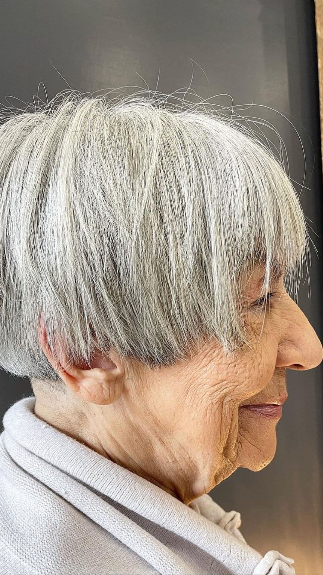 An older woman modelling a very short gray bob.