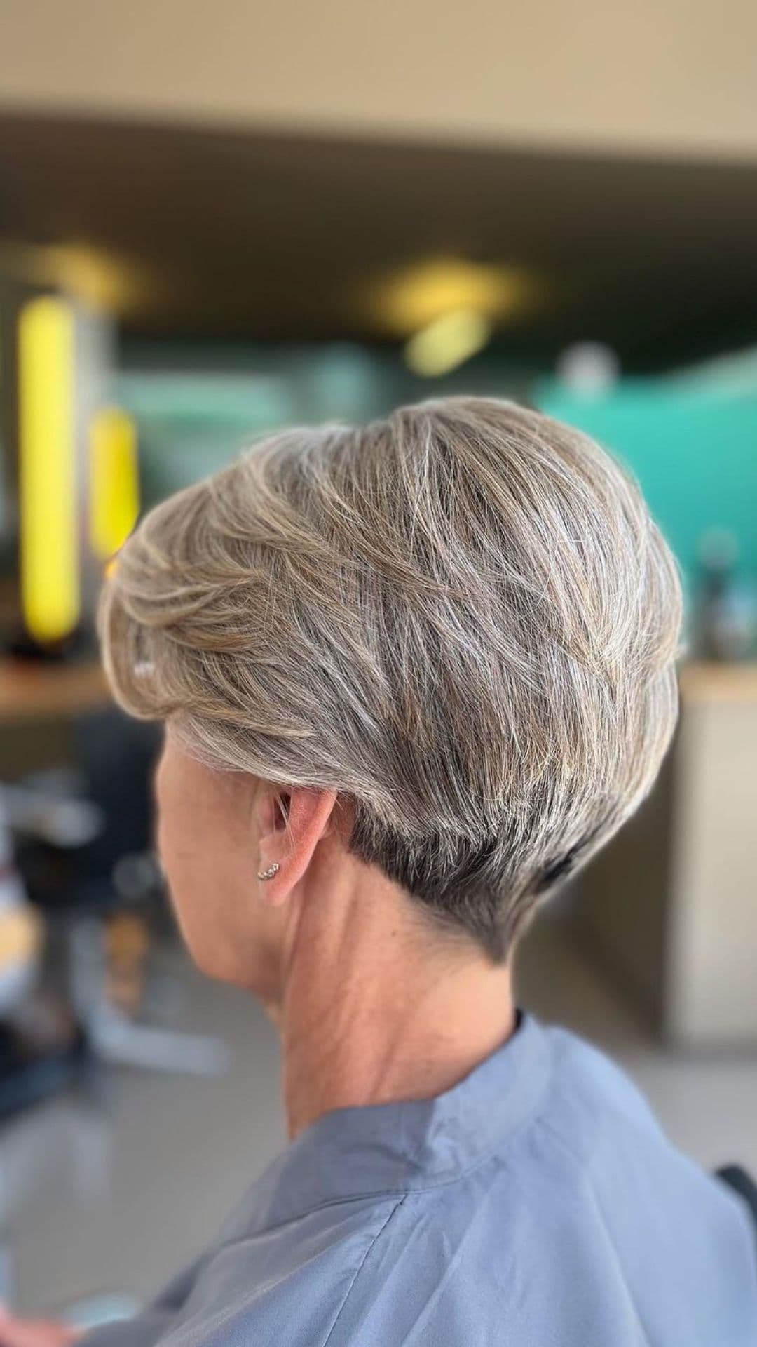 An older woman modelling a white and gray haircut with a layered back.