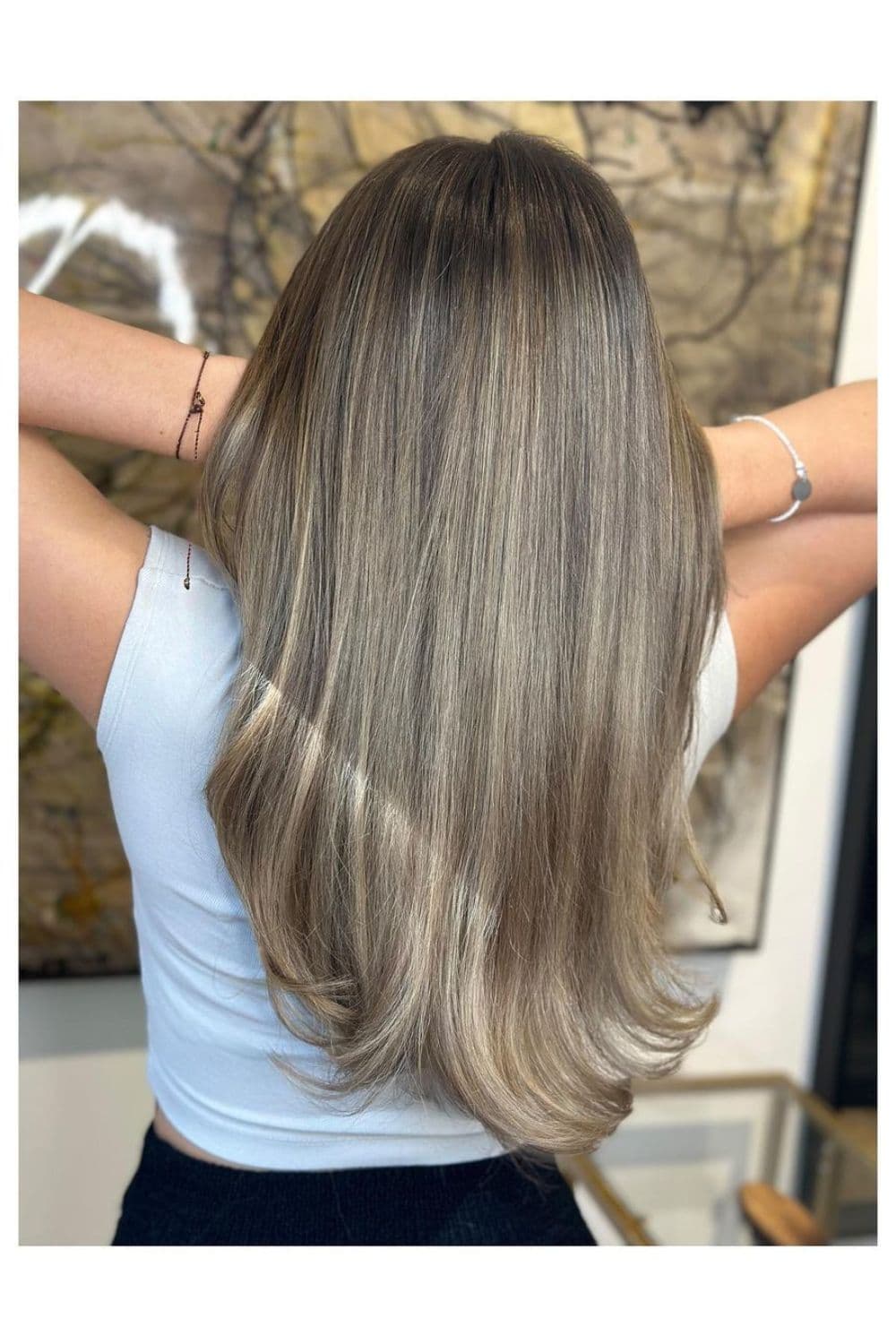 A woman with long straight ash blonde balayage.