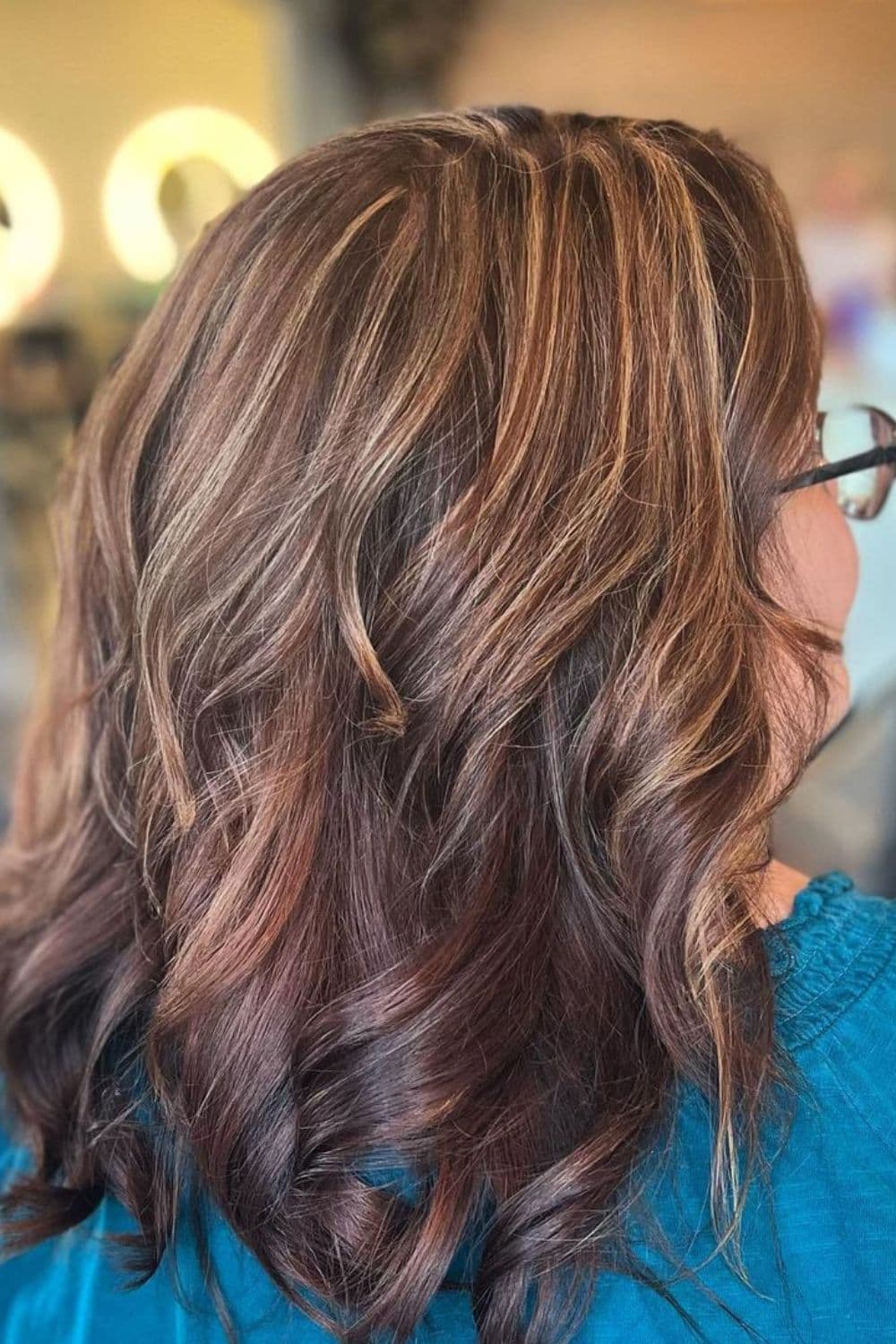 A woman with long bob brown hair with strawberry blonde highlights.