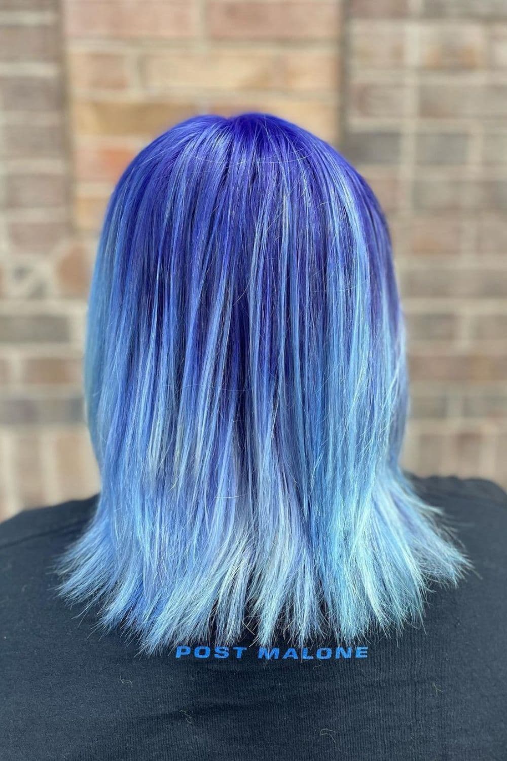 A woman in a long bob with dark blue roots with light blue tips.