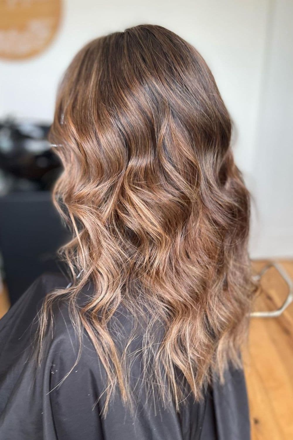 A woman with long dirty blonde and brown hair with waves.