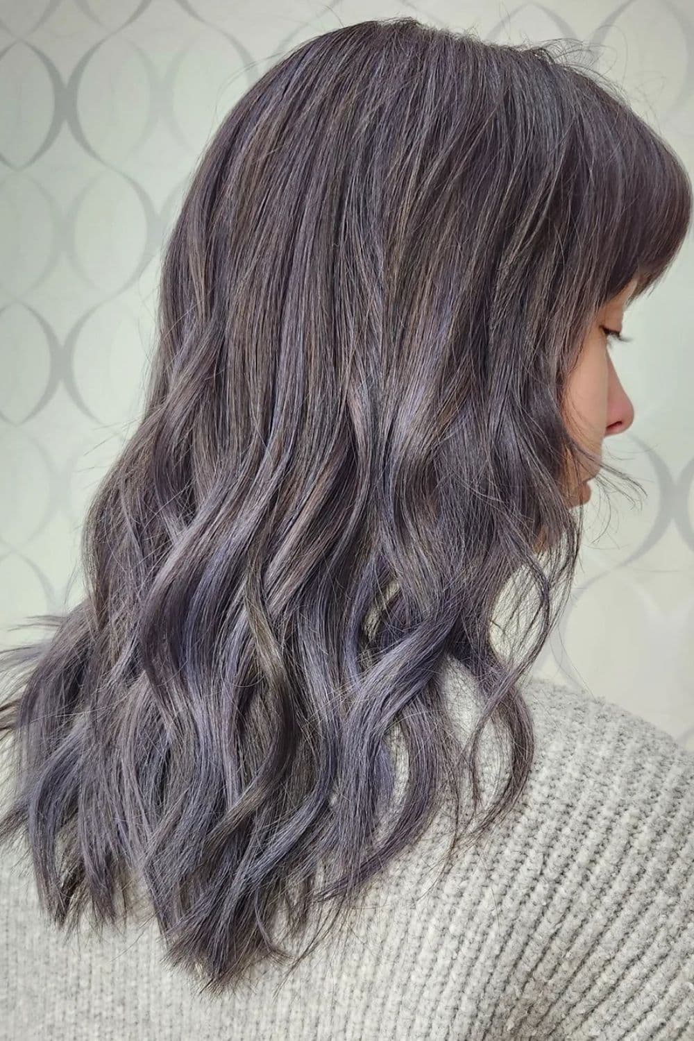 A woman with medium-length wavy lavender balayage.