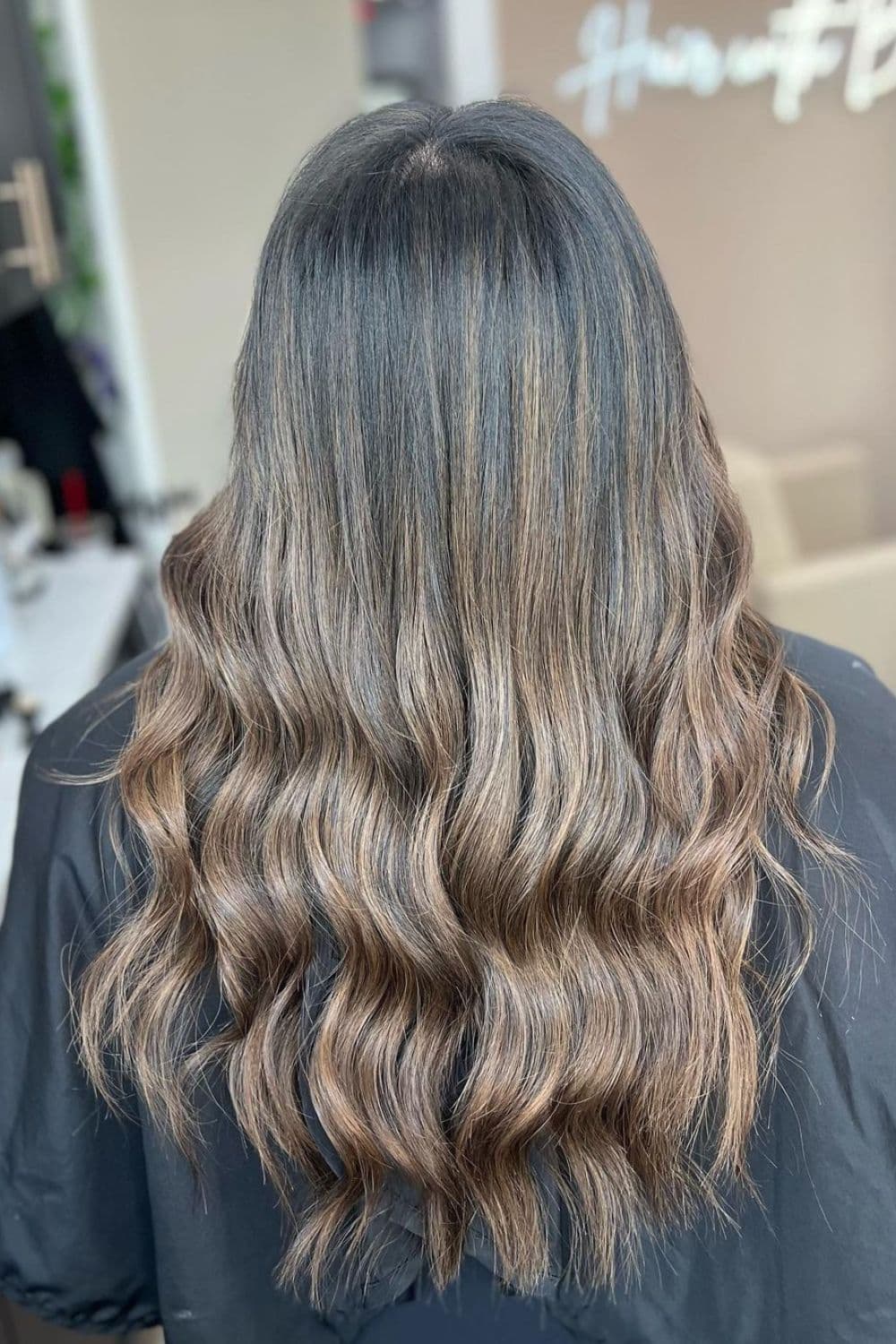 A woman with long wavy light brown balayage.