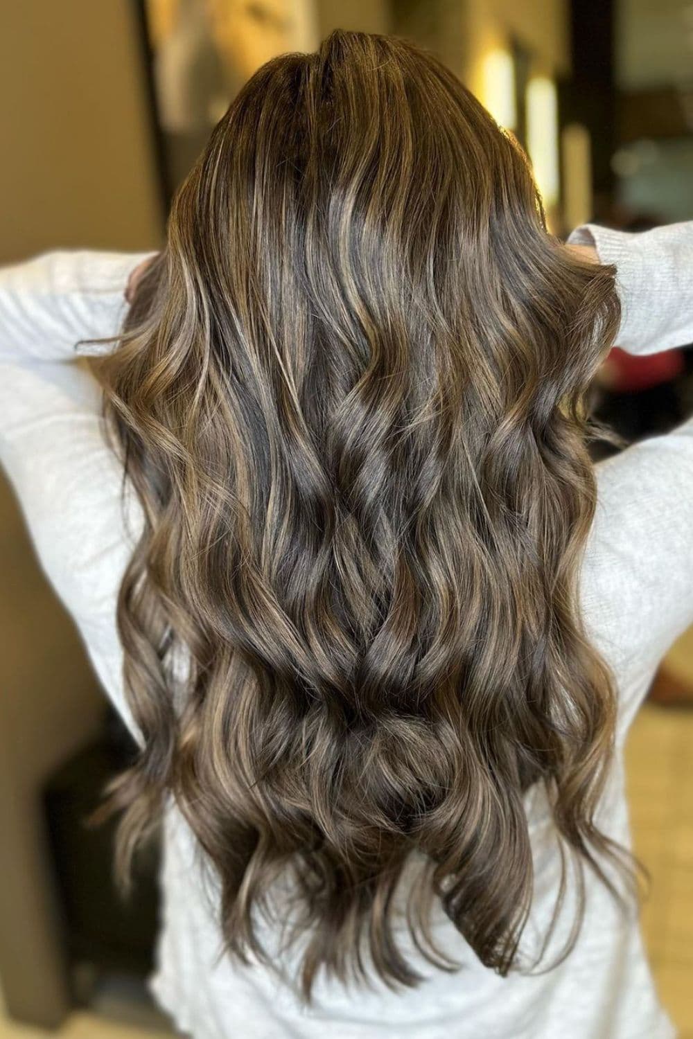 A woman with long wavy mushroom bronde balayage.