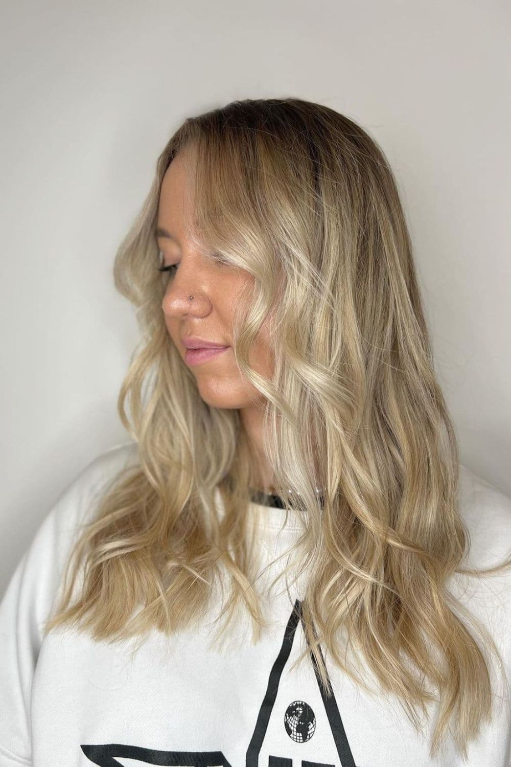 A woman with medium-length wavy pearl blonde balayage.