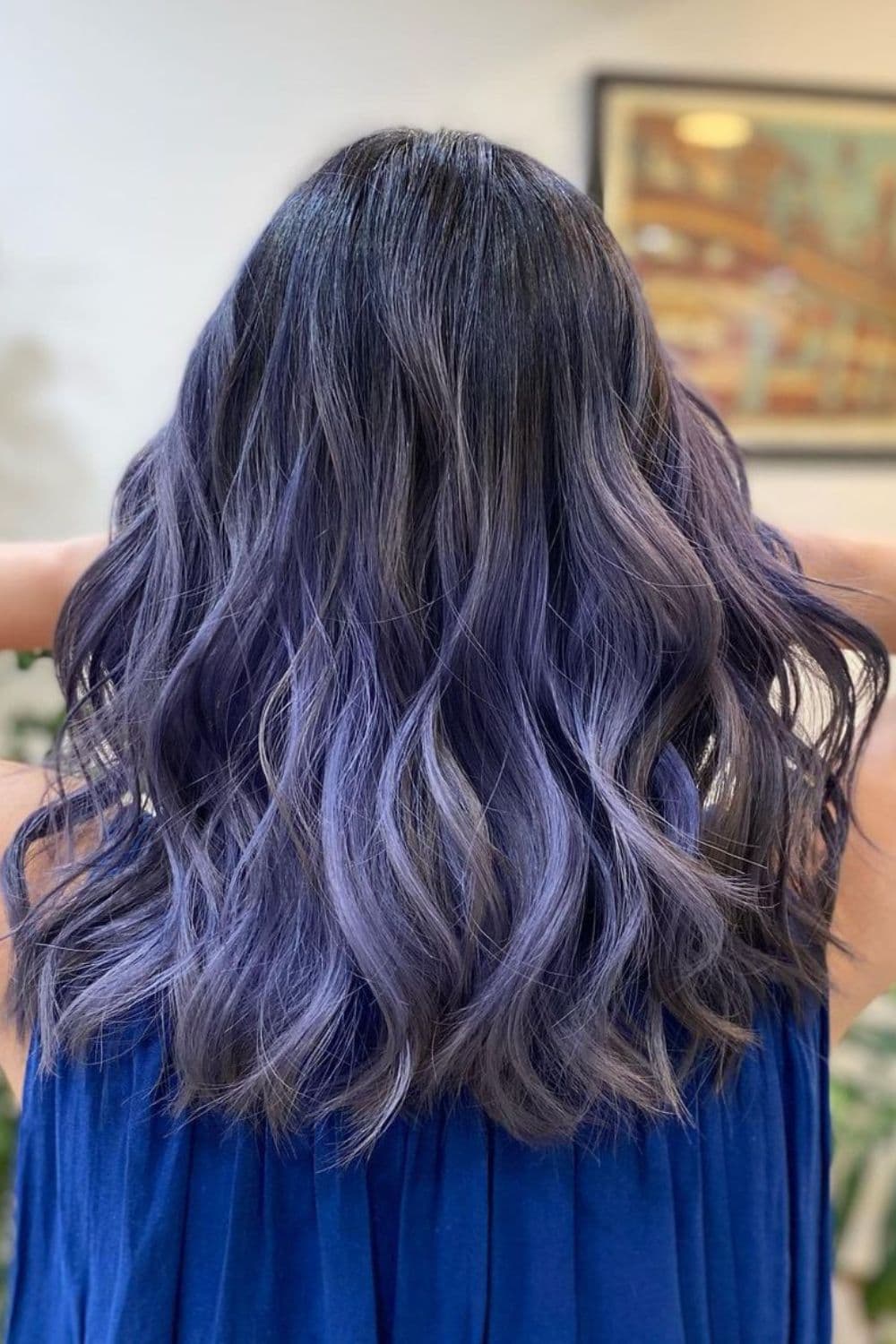 A woman with long wavy purple silver balayage.