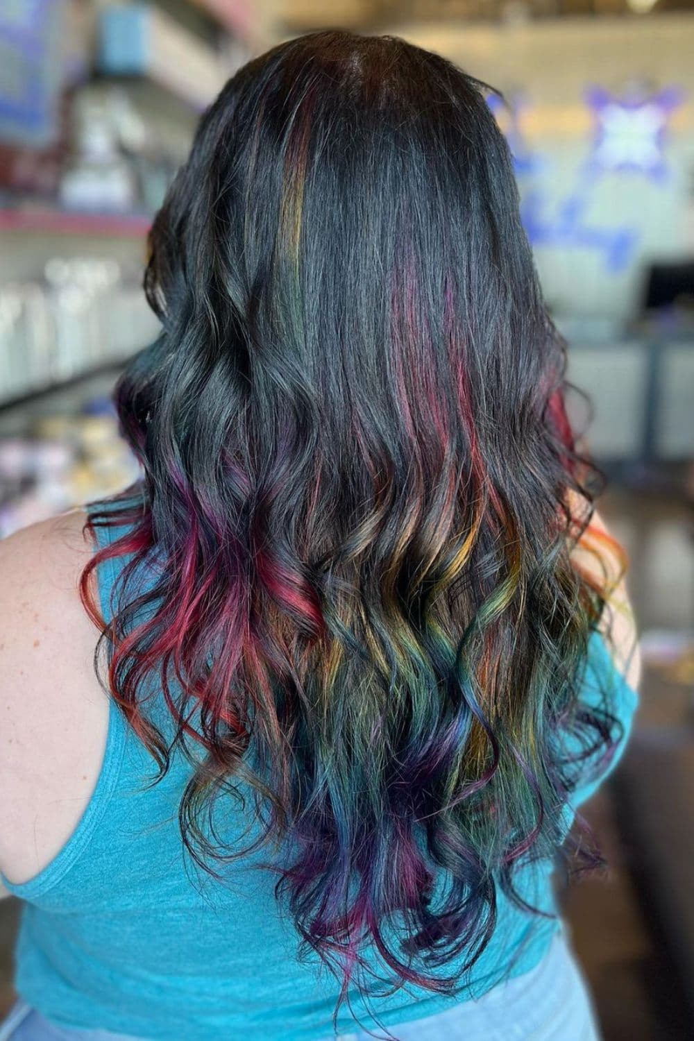 A woman with long black hair and rainbow balayage.