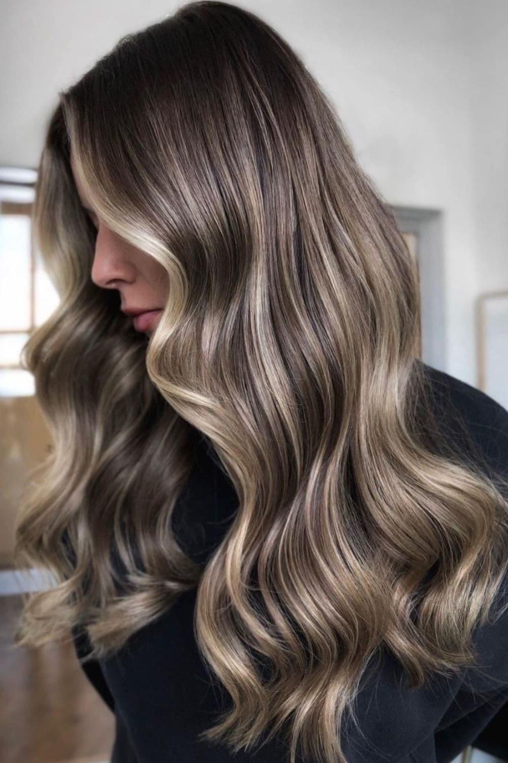 A woman with long wavy reverse balayage.