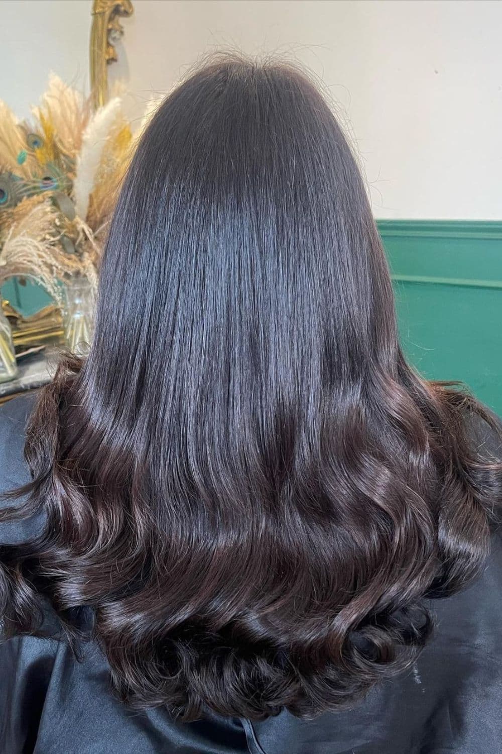 A woman with long sable brown hair with curly ends.