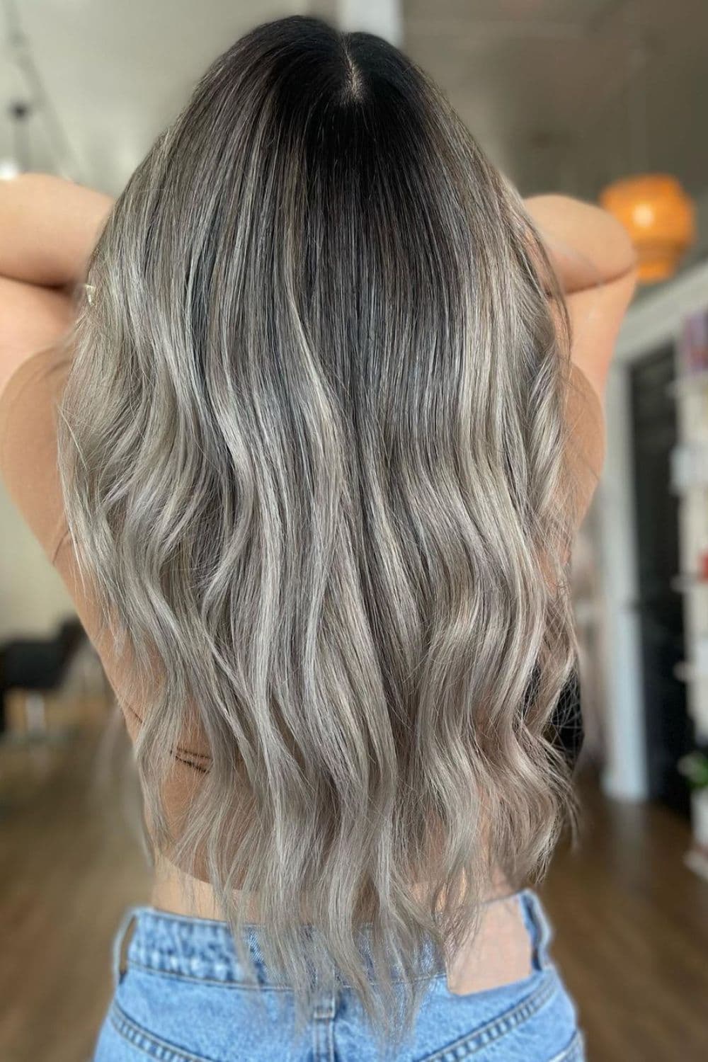 A woman with long wavy silver balayage.