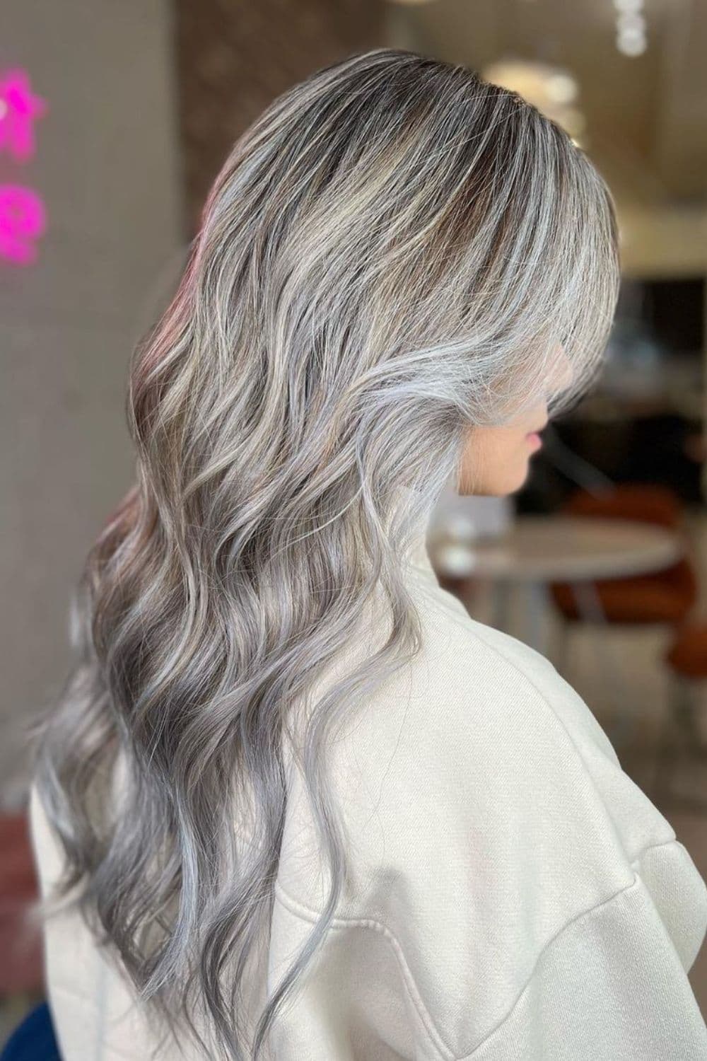 A woman with long wavy silver-gray balayage.