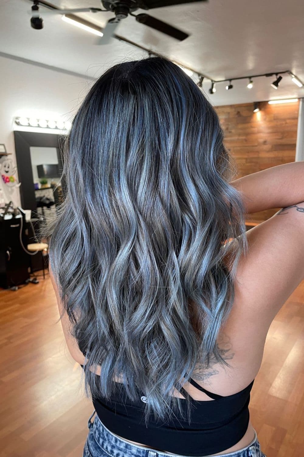 A woman with long steel blue hair with beach waves.