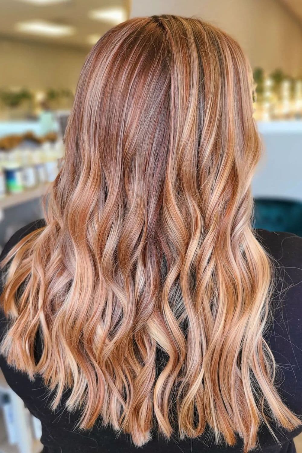 A woman with a long wavy strawberry blonde balayage.