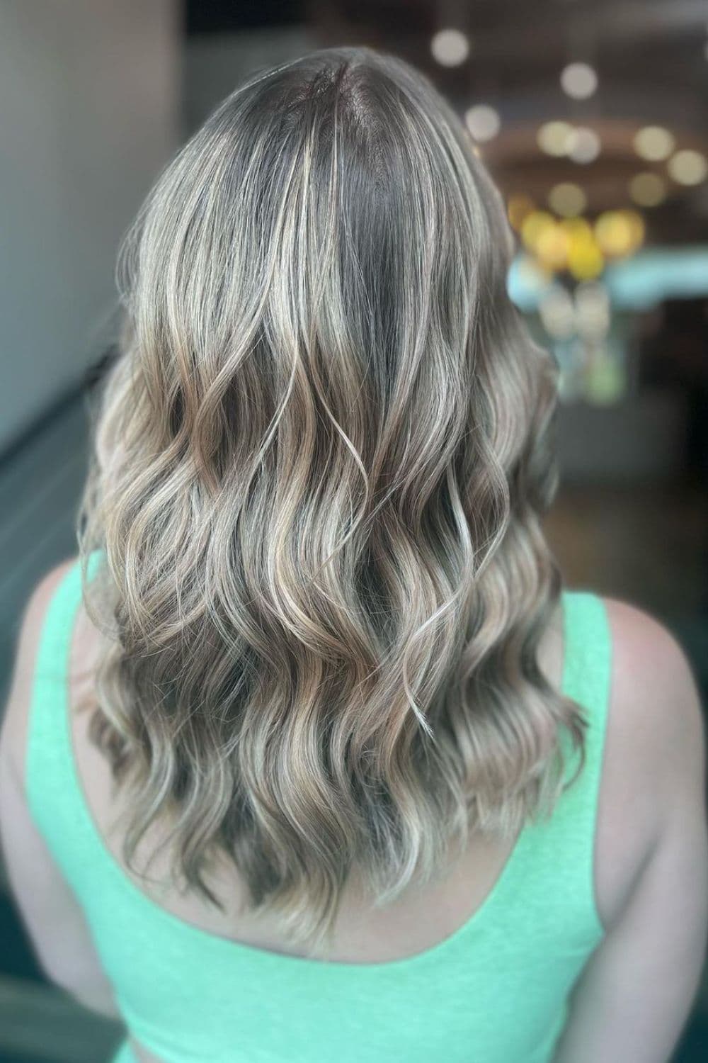 A woman with medium-length strawberry blonde hair with shadow roots.