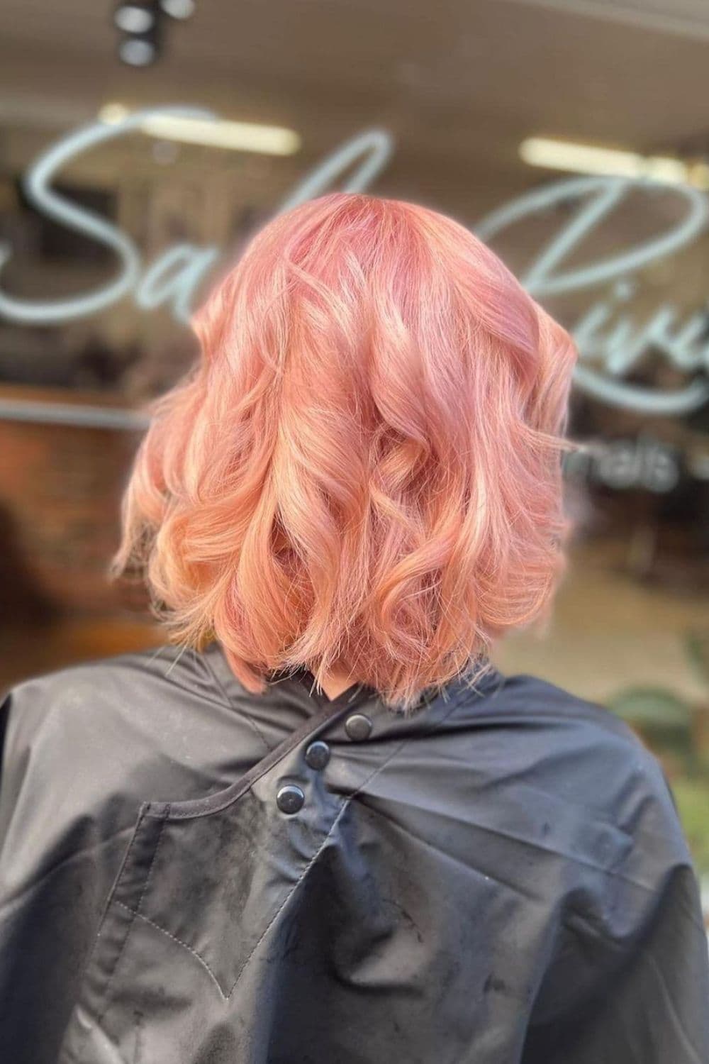 A woman with a strawberry pink bob with big curls.